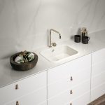 a wash area with a white sink against the El Calacatta Gold backsplash and countertop over the white cabinetry