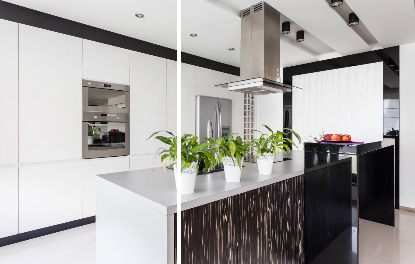 a kitchen with white cabinetry, stainless steel kitchen hood and kitchen appliances, and white kitchen island with decorative plant displays