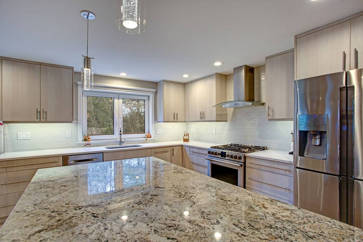 a beige countertop with brown veining and flecks in a kitchen with stainless steel appliances and neutral cabinet and wall colors