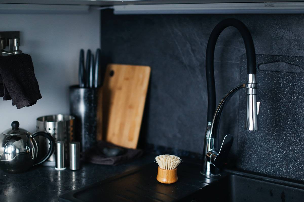 black granite countertop by the dark backsplash surface and stainless kitchen ware