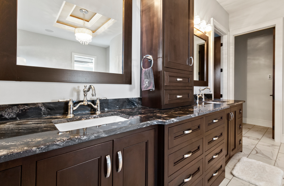 Vanity mirror with dark brown wooden cabinet and black marble countertop with white and gold streak pattern.