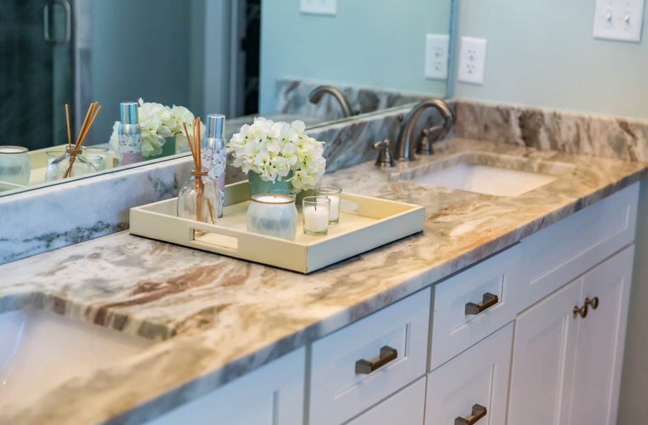 a marble countertop bathroom vanity with two sinks and a floral and scented decoration in the center
