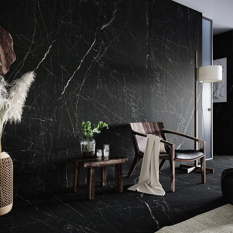 a room with floor to ceiling black marble tiles with white veins, a dark wooden chair with a throwaway blanket and a side table.