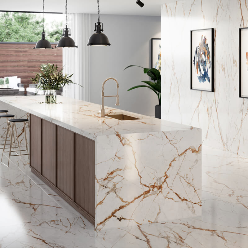 A kitchen with a white and gold marble floor, walls, and kitchen island countertop partnered with a gold and black stool chair, as well as gold accents on the sink and faucet.