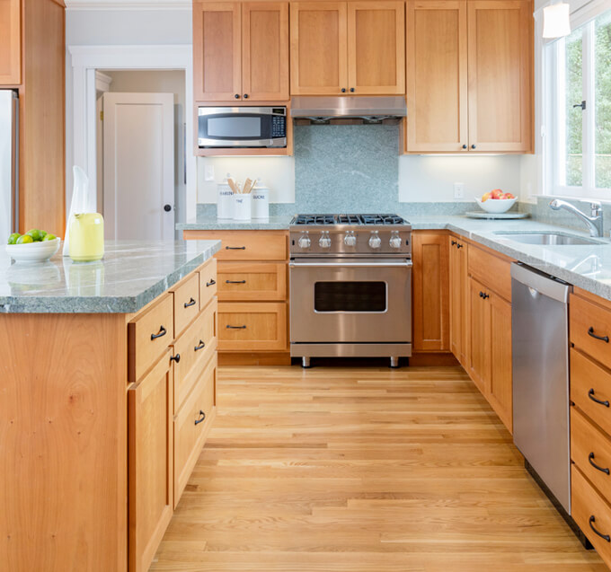 a simple kitchen with gray countertop, wooden cabinets, and built-in appliances