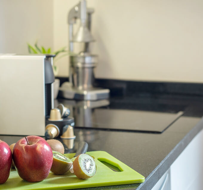 apple and kiwi fruit slices on a chopping board over a black countertop