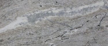 a Fantasy Brown marble countertop surface that has brown and sandy hues with a flowing pattern of white, brown, and gray veins with black spots throughout